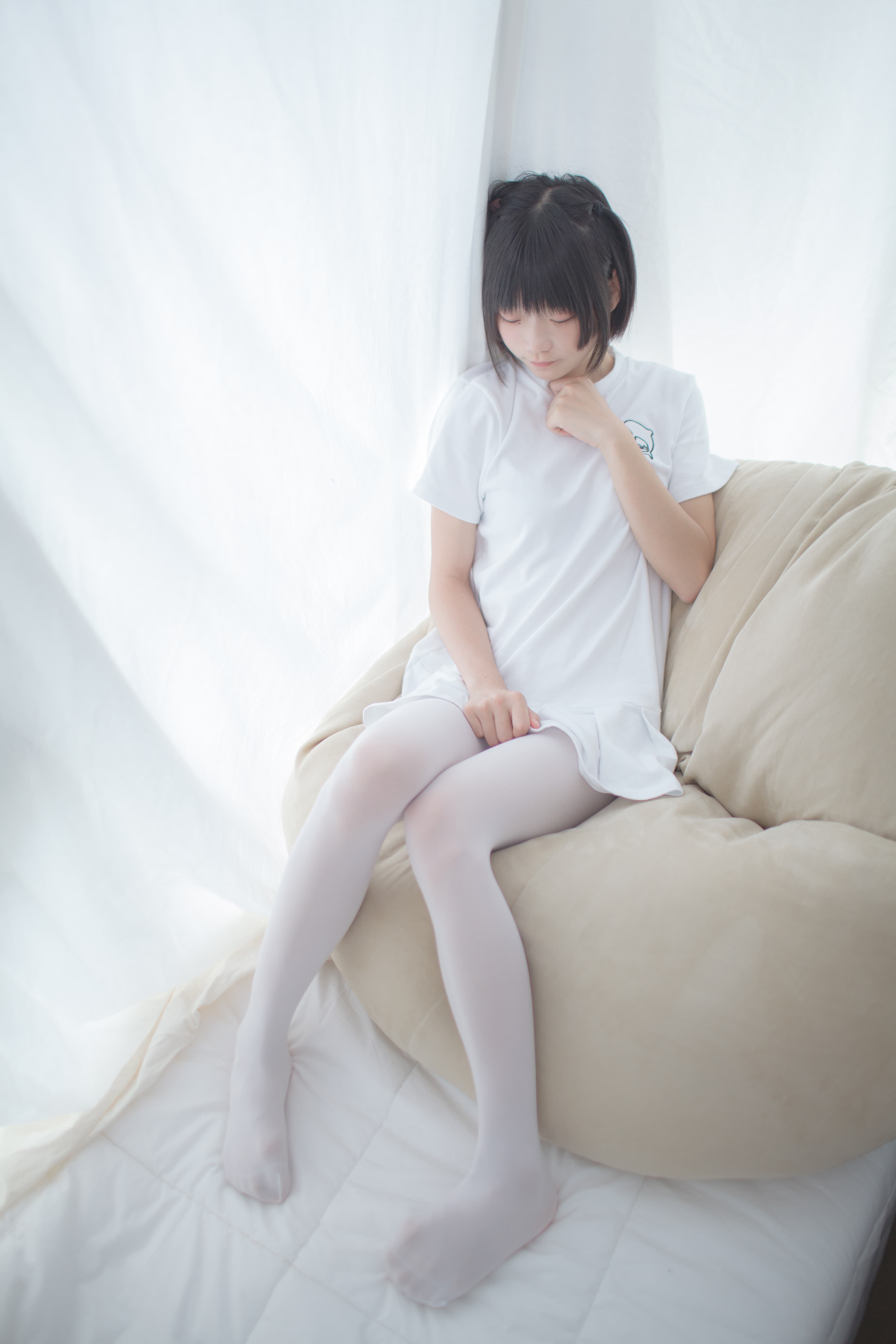 Model reclining with legs crossed showing pristine white nylon and partial bare toes